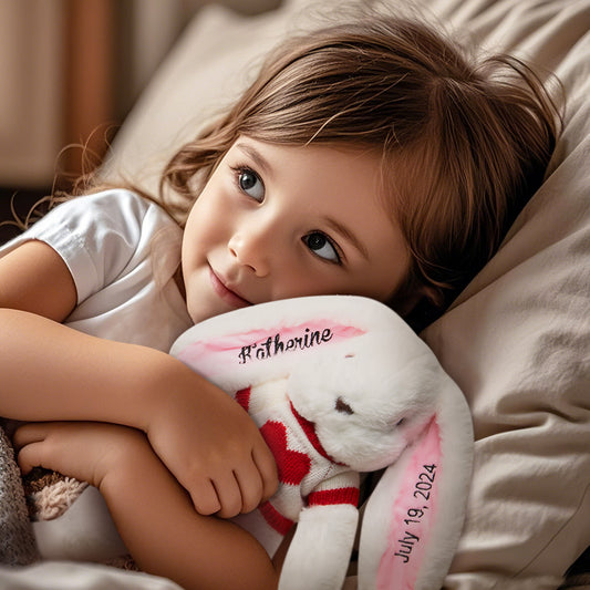 Child cuddling a personalized bunny plush toy with embroidered name and red heart detail, a perfect custom gift.